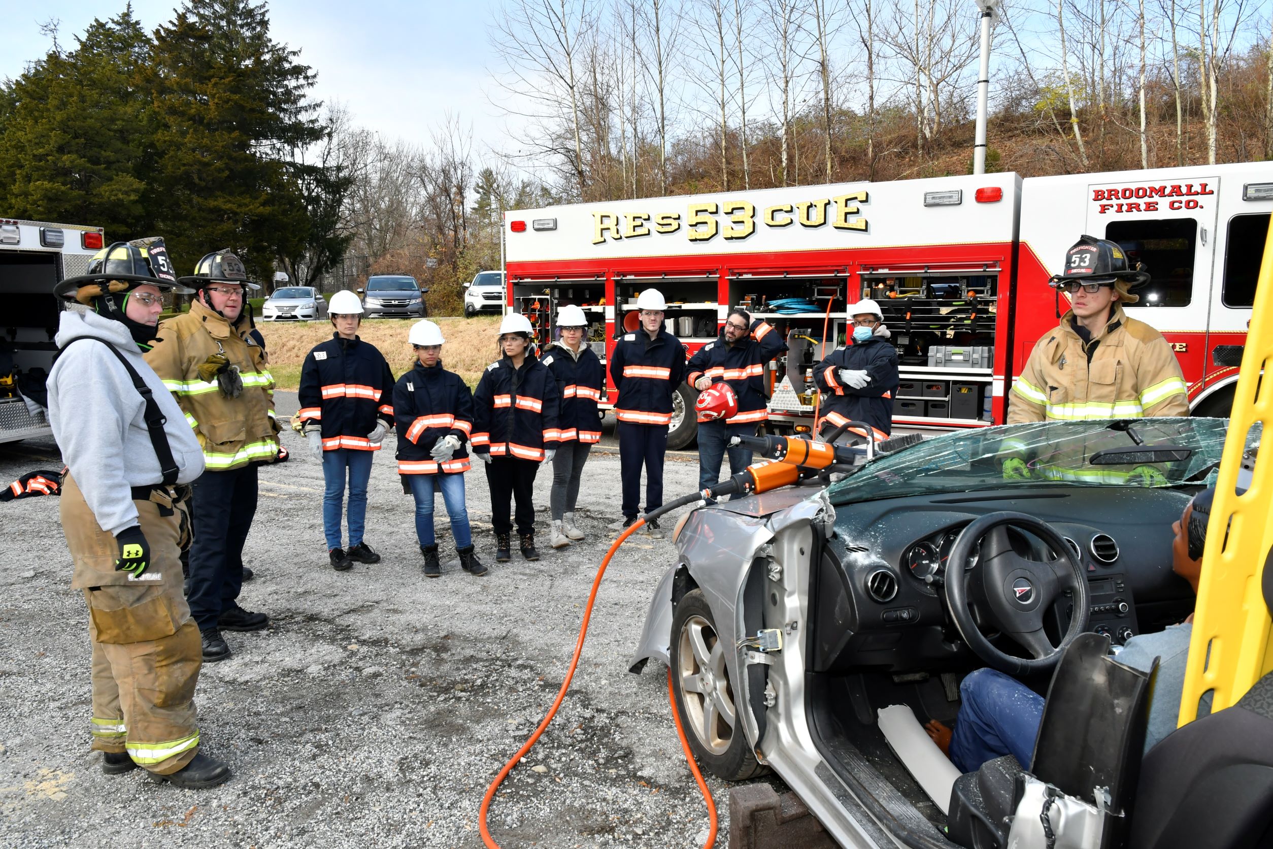 EMS-100 students pay close attention to Broomall Fire Company firefighters before using hydraulic rescue tools to extricate a simulated male manikin trapped in a ca