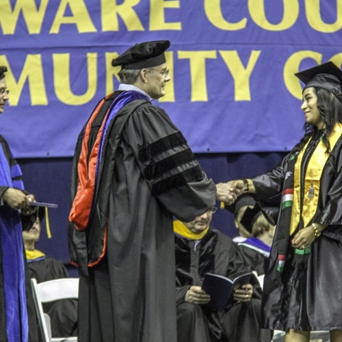 Graduate walks across the stage, shakes hands with college officials