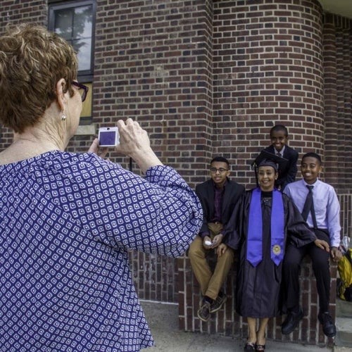 Woman taking photo of student posing for picture with loved ones