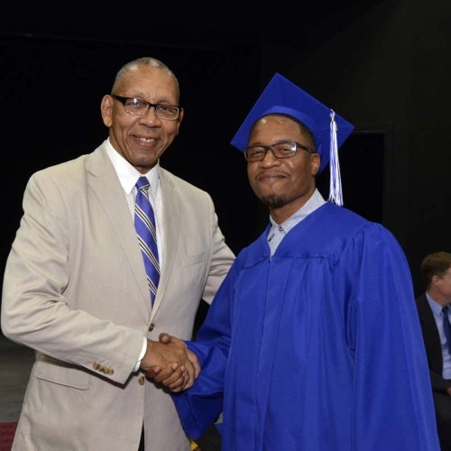 Graduate shaking hands with man.