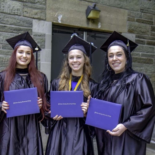 Three graduates pose with diplomas