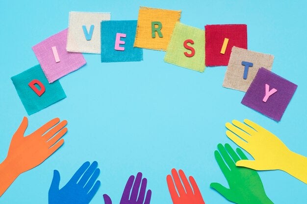Colorful cut-out letters spelling 'Diversity' above a semi-circle of vibrant paper hands on a light blue background.