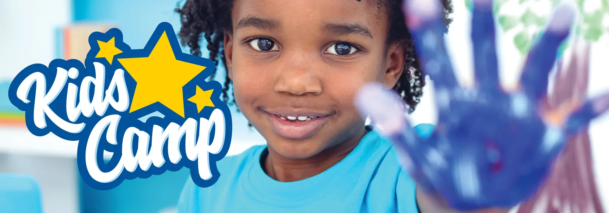 A young child smiling and showing their hand covered in blue paint, with a vibrant 'Kids Camp' logo featuring stars in the background.