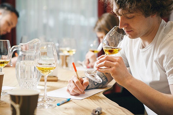 male student smelling wine and taking notes