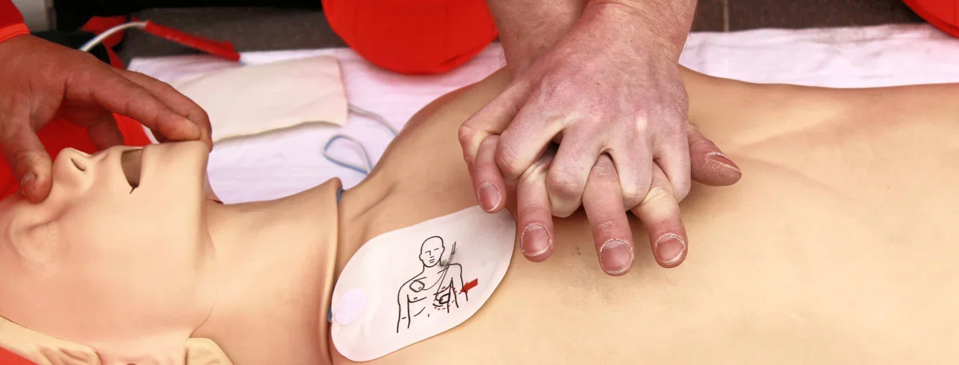 Close-up of hands performing chest compressions on a CPR mannequin during a first-aid training session.