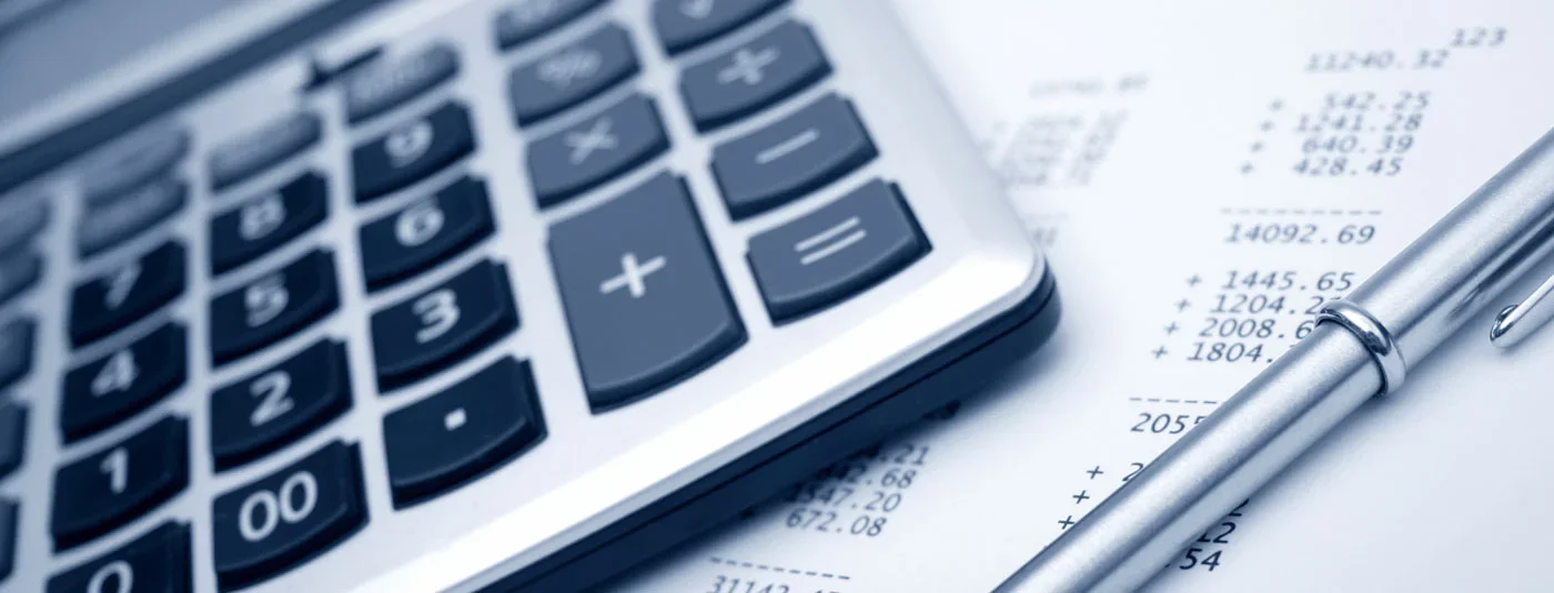 Close-up of a calculator and a pen placed on a financial document with numbers and calculations.