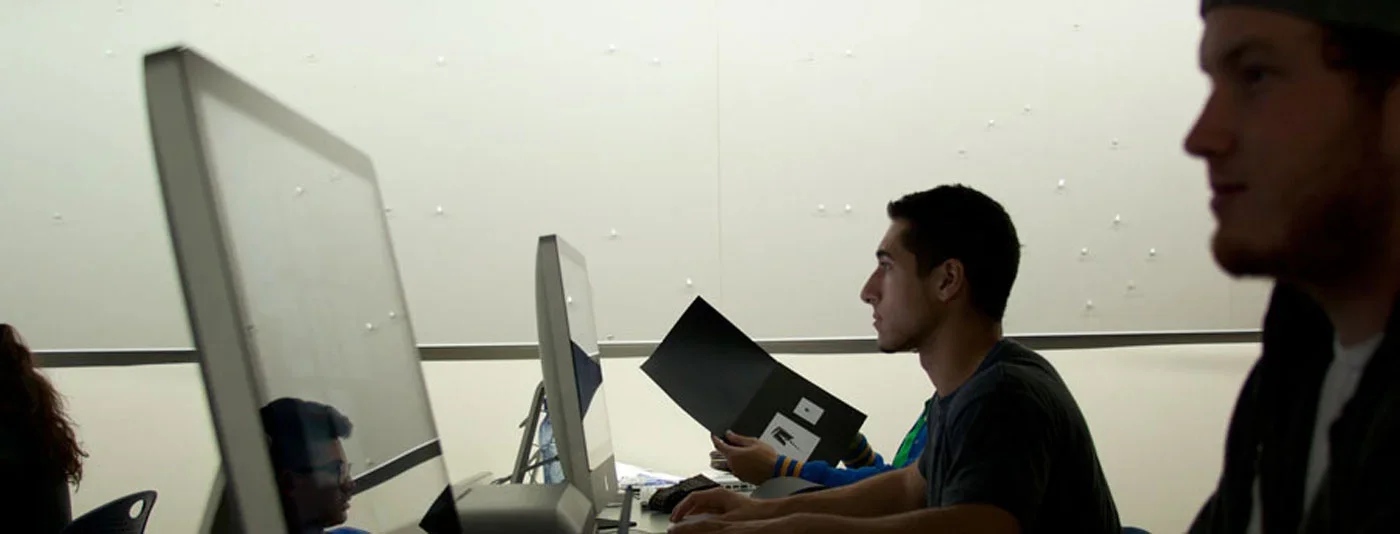 Students working attentively on desktop computers in a graphic design classroom.