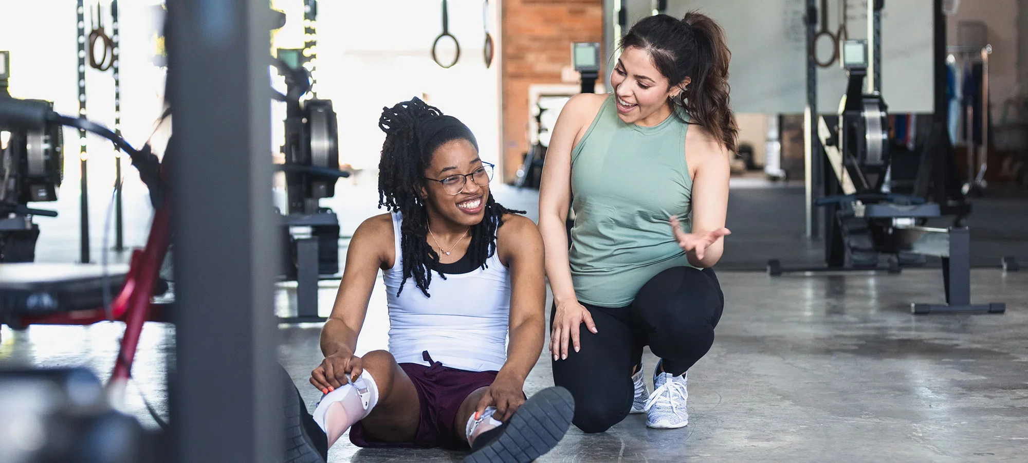 A personal trainer encouraging and supporting an athlete with a prosthetic leg during a workout session in a gym.
