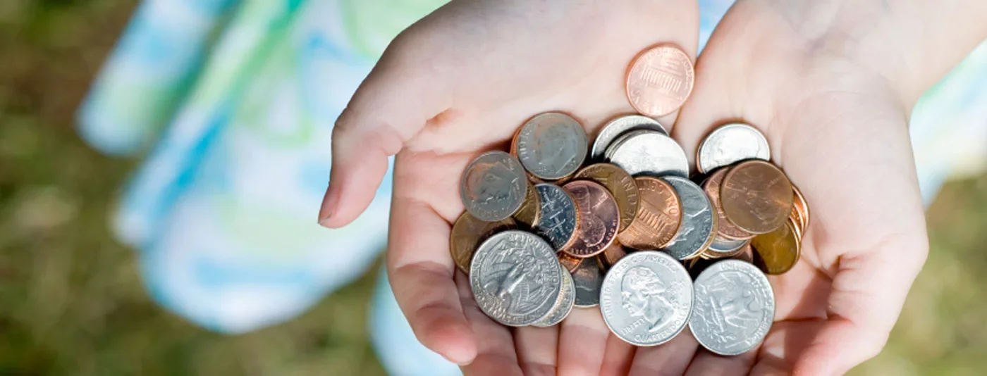 Hands holding a collection of coins, symbolizing savings, donations, or small contributions for fundraising