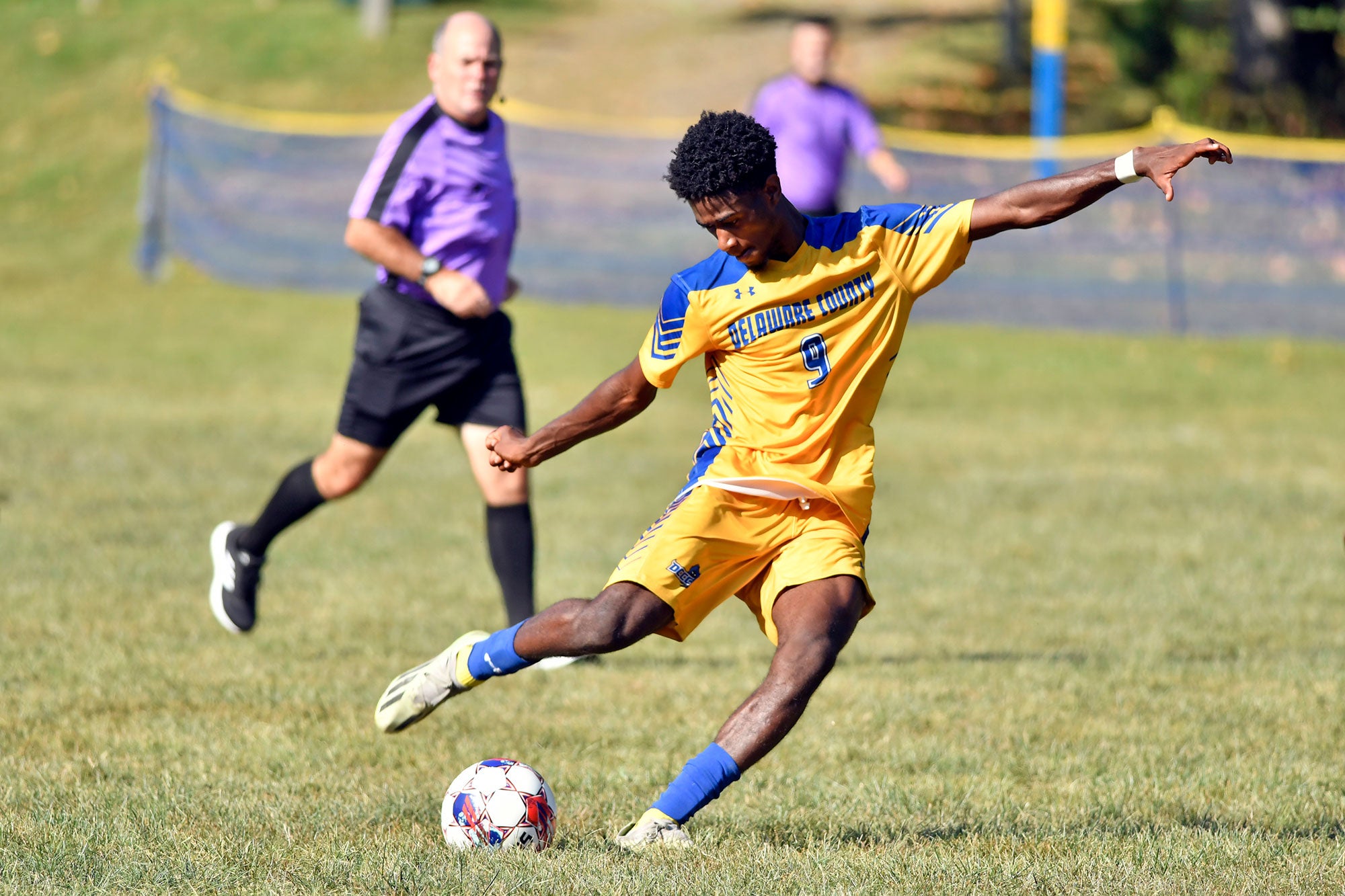 College soccer player kicking the ball mid-game