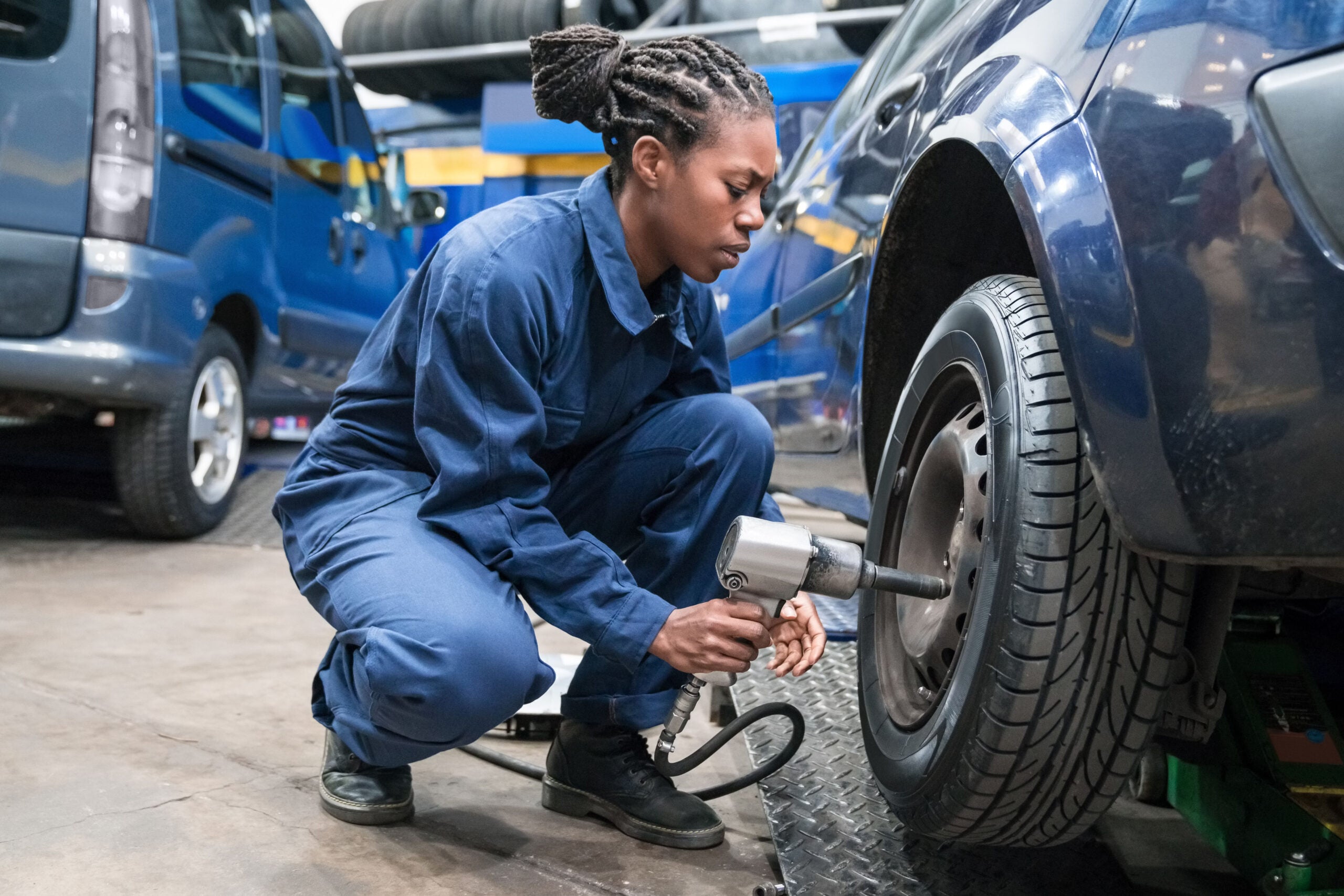Female auto tech employee or student, replacing a car wheel