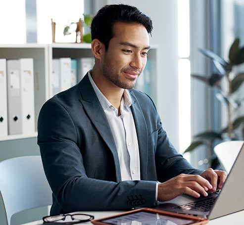 person sitting at desk typing on laptop