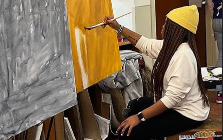 Student working at easel in studio class