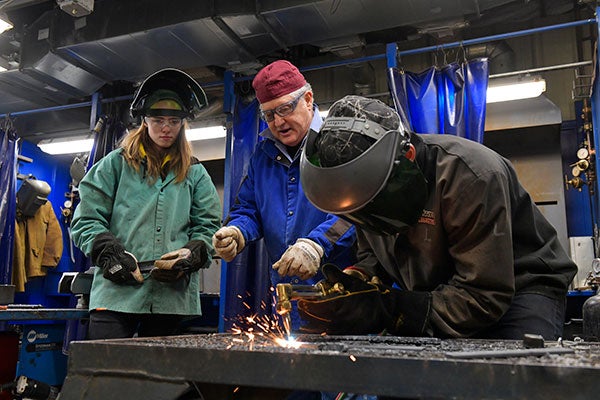 welding student working with instructor and classmate