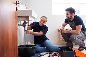 person at home fixing sink pipe