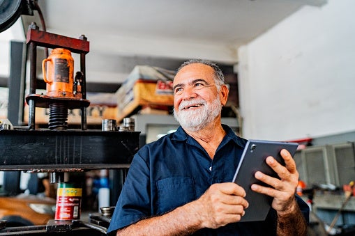 Senior-aged man using tablet to manage automotive business