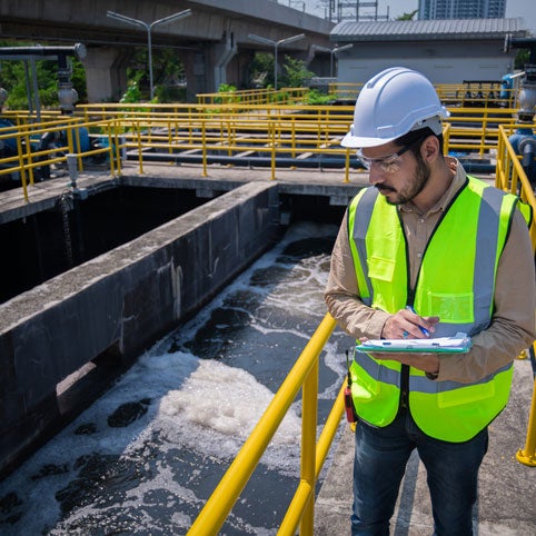 Employee standing over water treatment container